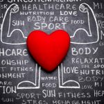 A red heart and strong body drawn on a chalkboard with health related words