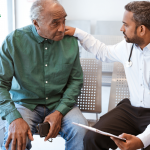 Elderly man in green shirt meeting with his doctor